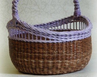 May include: A woven basket with a purple handle and a brown base. The basket is oval shaped and has a woven pattern.