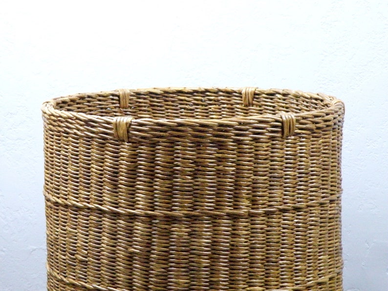 Op de afbeelding: Een geweven rieten mand met een ronde bovenkant en een natuurlijke bruine kleur.