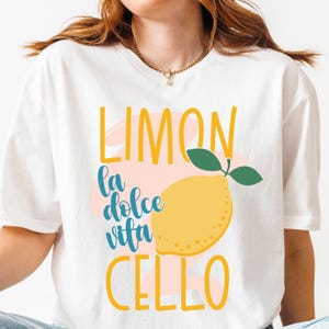 May include: White t-shirt featuring a lemon-themed design. The design includes the word "LIMON" in yellow, "la dolce vita" in teal, and "CELLO" in yellow, alongside a yellow lemon illustration with green leaves.
