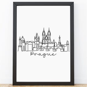 May include: A framed wall art print featuring a black continuous line drawing of the Prague city skyline on a white background. The word Prague is written in a black cursive script font below the architectural outline of the city buildings.