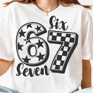 May include: White t-shirt with a black design of the numbers "67". The number "6" is decorated with stars, and the number "7" has a chequered pattern. The words "Six" and "Seven" are written above and below the numbers.