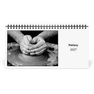 May include: A black and white spiral-bound desk calendar featuring a photograph of hands shaping clay on a pottery wheel. The right side of the calendar displays the text Pottery 2027 in a clean, black sans-serif font against a plain white background.
