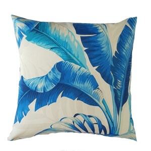 May include: A white cushion with a blue and turquoise tropical leaf pattern.