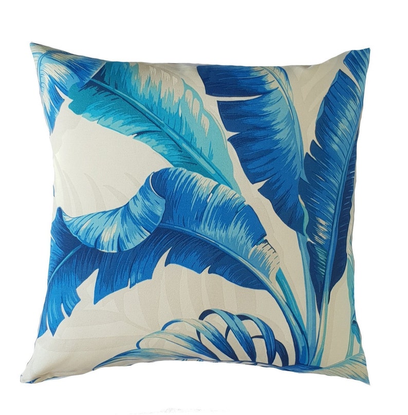 May include: A white cushion with a blue and turquoise tropical leaf pattern.