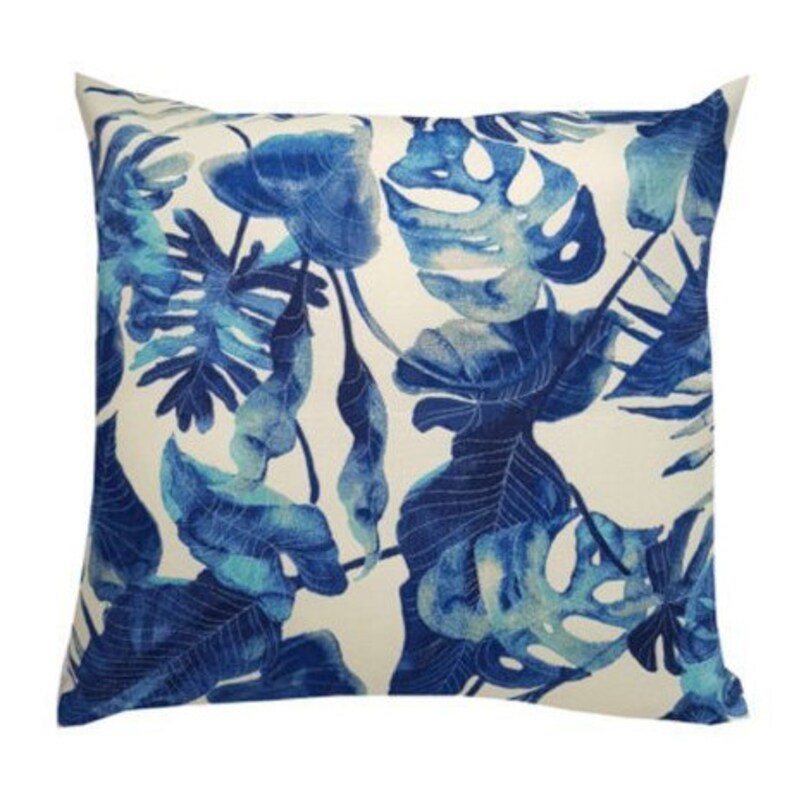 May include: A white cushion with a blue and teal tropical leaf pattern.