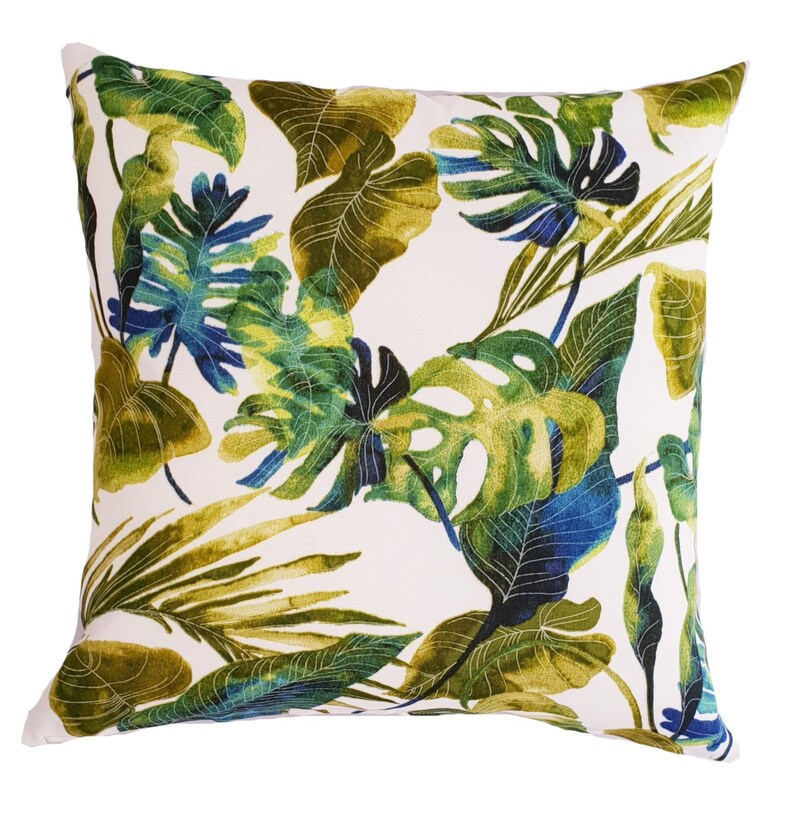 May include: A white cushion with a tropical leaf pattern in shades of green and blue.