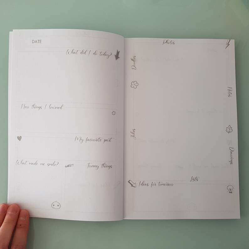 May include: A blank, white, two-page spread of a journal with prompts for daily reflection. The left page has prompts for "What did I do today?", "New things I learned", "My favorite part", "What made me smile?", and "Funny things". The right page has prompts for "Photos", "Doodles", "Jokes", "Ideas for tomorrow", "Lists", "Notes", and "Drawings".