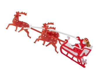 May include: A plastic Christmas decoration featuring Santa Claus in a red sleigh pulled by two orange reindeer with white spots. The sleigh has red and white details, and the reindeer are connected by a white plastic line.