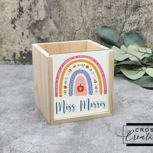 May include: Wooden pencil holder with a rainbow design and the words "Teach, Love, Inspire, Encourage, Lead, Connect" around the rainbow. The words "Miss Morris" are printed below the rainbow.