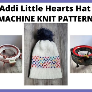 K&ouml;nnte beinhalten: Wei&szlig;e Strickm&uuml;tze mit einem bunten Herzmuster und einem schwarzen Bommel. Die M&uuml;tze wird mit zwei runden Strickmaschinen gezeigt.