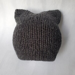 May include: A gray knitted beanie with cat ears. The beanie is made of a soft, fuzzy yarn.