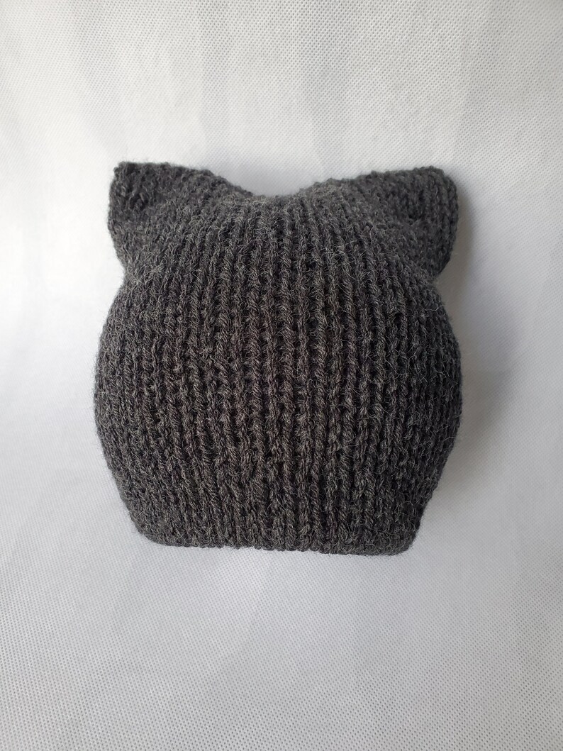 May include: A gray knitted beanie with cat ears. The beanie is made of a soft, fuzzy yarn.