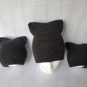May include: Three gray knitted cat ear hats of different sizes. The hats are made of a soft, fuzzy yarn and have a simple, classic design.