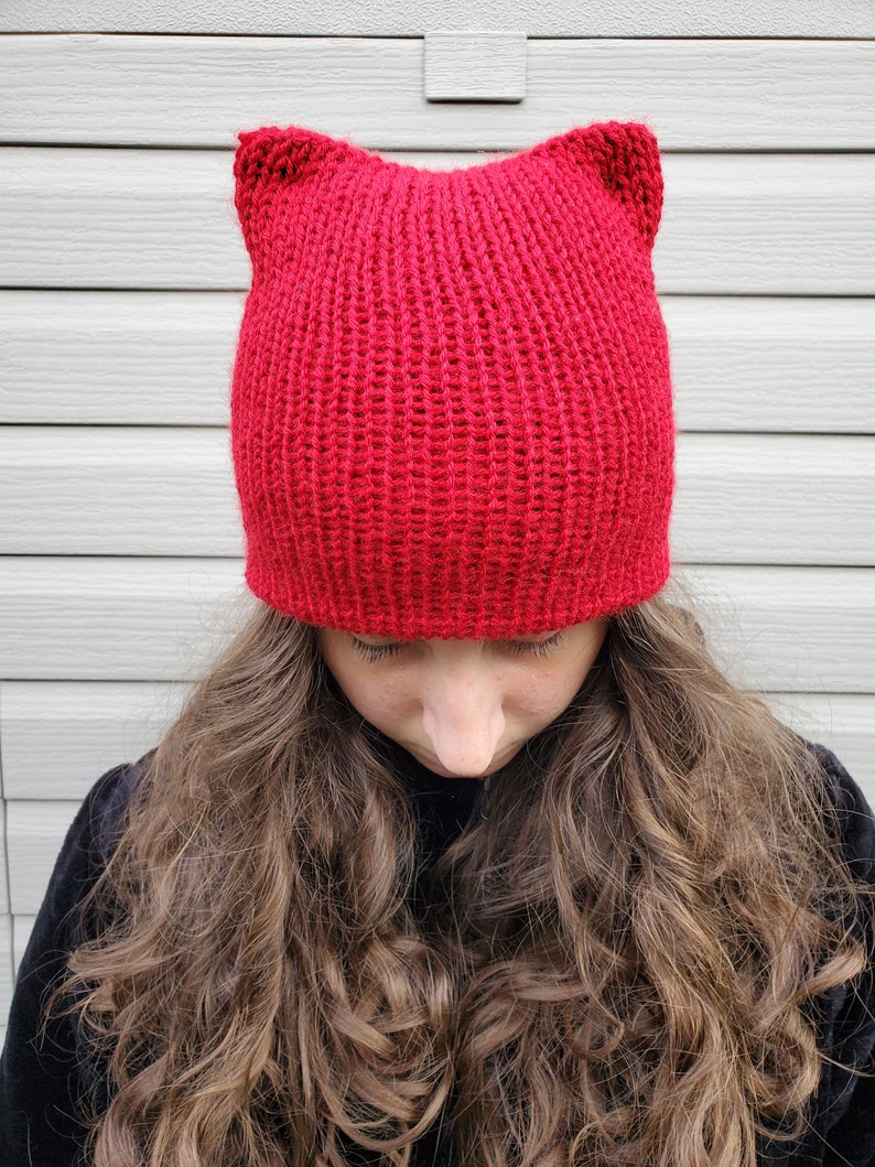 May include: A red knitted beanie with cat ears. The beanie is made of a soft, warm yarn and is perfect for keeping your head and ears warm in the winter.
