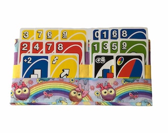May include: A colorful fabric case with a rainbow and owl design holds a deck of UNO cards. The cards are arranged in two rows, with the numbers 3, 7, 6, 9, 2, 4, 7, 8, 0, 1, 6, 8, 1, 3, 5, 9, +4, and a wild card visible.