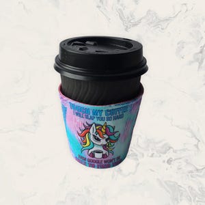 May include: A black disposable coffee cup with a black lid and a colourful fabric sleeve. The sleeve features a cartoon unicorn with a rainbow mane and the text: TOUCH MY COFFEE I WILL SLAP YOU SO HARD EVEN GOOGLE WON'T BE ABLE TO FIND YOU.