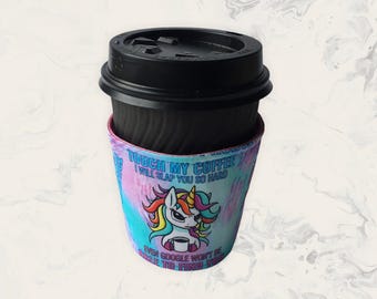 May include: A black disposable coffee cup with a black lid and a colourful fabric sleeve. The sleeve features a cartoon unicorn with a rainbow mane and the text: TOUCH MY COFFEE I WILL SLAP YOU SO HARD EVEN GOOGLE WON'T BE ABLE TO FIND YOU.