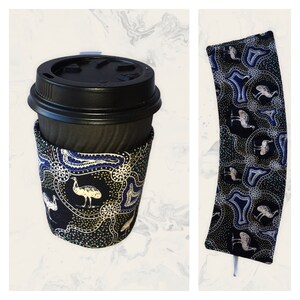 May include: A black coffee cup with a colourful fabric sleeve featuring an aboriginal design with white birds and gold dots. The sleeve is also available as a separate item.