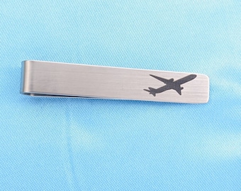 May include: A silver tie clip with a silhouette of an airplane.