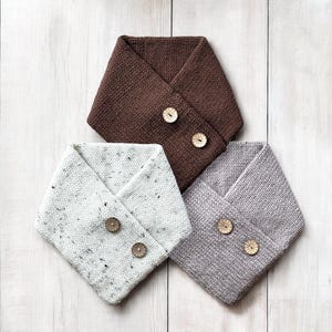 May include: Three knitted neck warmers with wooden button closures. The neck warmers are brown, white with black flecks, and gray.