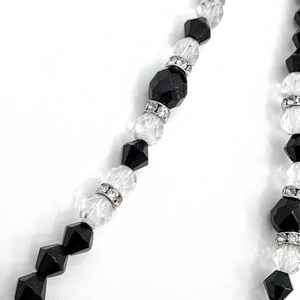 May include: A necklace with alternating black and clear faceted beads. The clear beads are separated by silver-toned spacers. The necklace has a classic design, suitable for various occasions.