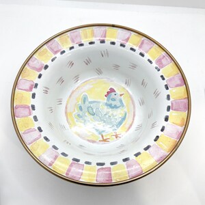 May include: A decorative ceramic bowl with a hand-painted chicken design. The bowl features a yellow and pink checkered border with a gold rim. The chicken is light blue with a red comb, set against a yellow background.