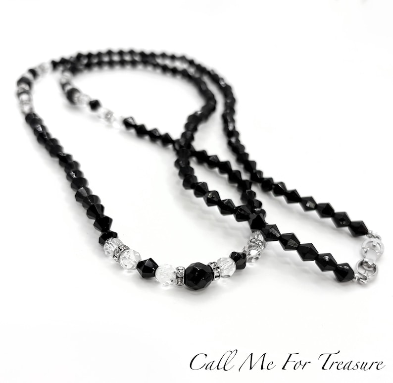 May include: A black beaded necklace with clear crystal accents and a silver clasp. The necklace features a mix of faceted and round beads, creating a sparkling effect. The text "Call Me For Treasure" is at the bottom.