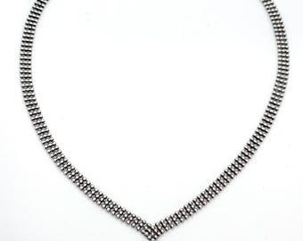 May include: A silver-toned necklace featuring a multi-strand beaded chain design that forms a V-shape at the centre. The necklace includes a metallic lobster claw clasp at the top for closure. The text "Call Me For Treasure" is visible at the bottom.