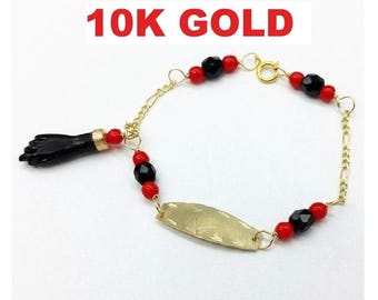 Op de afbeelding: Een 10K gouden armband met een zwarte handvormige bedel, een centrale gouden plaat en afwisselende rode en zwarte kralen. De ketting bestaat uit gouden schakels en een veerringsluiting. De tekst 10K GOLD is zichtbaar boven het sieraad.