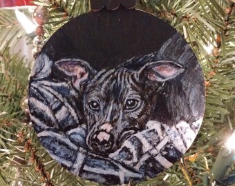May include: A black and white painted Christmas ornament featuring a dog's face with a black background.