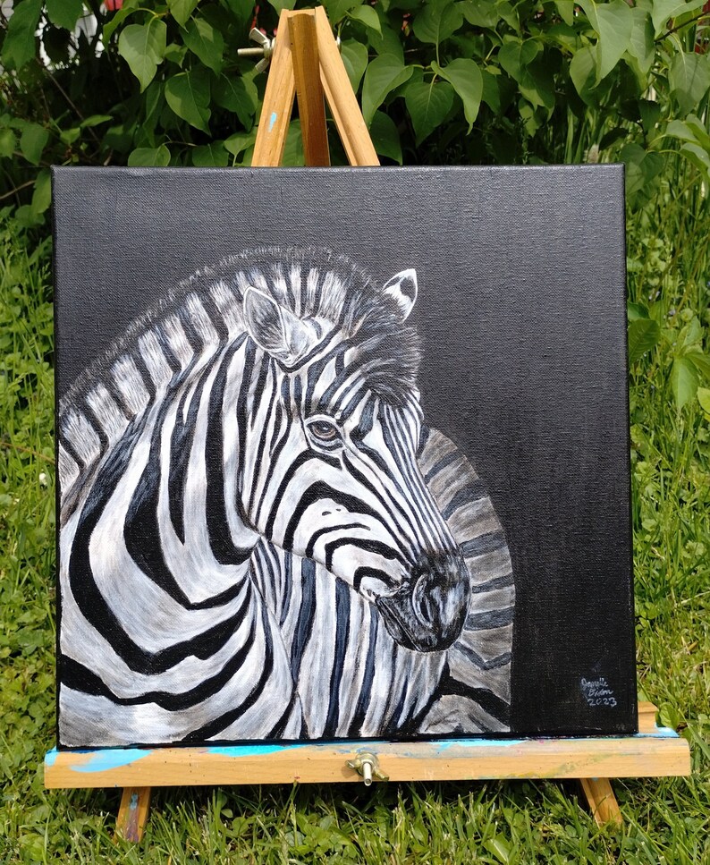 May include: A black and white zebra painting on a black canvas. The zebra is facing the right side of the painting and has its head turned to the left. The zebra's stripes are painted in a realistic style. The painting is signed and dated in the bottom right corner.