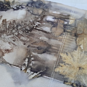 May include: A close-up of a piece of fabric with a brown and gold leaf pattern. The fabric has a textured surface and appears to be made of natural fibers.