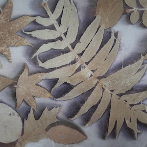 May include: A close-up of a fabric with a variety of pressed leaves in shades of brown and beige. The leaves are arranged in a random pattern and create a natural, organic design.