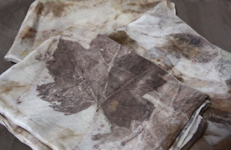 May include: A set of three silk scarves with a natural dye pattern of leaves in shades of brown and beige.