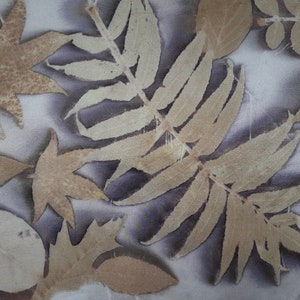 May include: A close-up of a fabric with a variety of pressed leaves in shades of brown and beige. The leaves are arranged in a random pattern and create a natural, organic design.