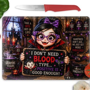 Puede incluir: Una tabla de cortar rectangular de cristal con un personaje vampiro de dibujos animados que sostiene un cartel que dice I DON'T NEED BLOOD TYPE... POSITIVE IS GOOD ENOUGH! Incluye un cuchillo de mango rojo, un pimiento verde y tomates rojos.