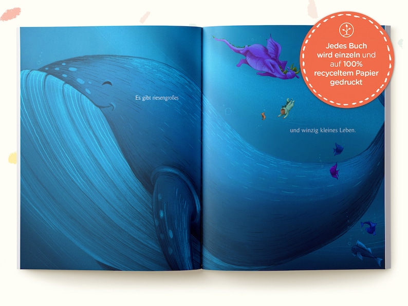 May include: An open book with an illustration of a whale and a purple dragon in the ocean. The text on the page reads "Es gibt riesengrolles" and "und winzig kleines Leben." The book cover has a red circle with a plant icon and the text "Jedes Buch wird einzeln und auf 100% recyceltem Papier gedruckt."