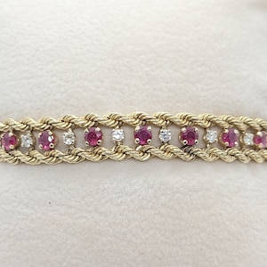 May include: A gold rope chain bracelet with alternating red rubies and clear diamonds.
