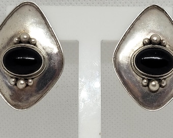 May include: A pair of silver earrings with black gemstone accents. The earrings are shaped like diamonds and have a silver bezel setting around the black gemstones.