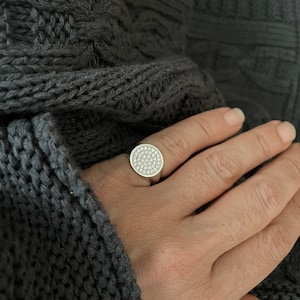 Close up of a ladies pinky ring with diamonds.