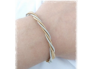 Guitar string bracelet made with silver and gold colored stainless steel guitar strings. Strings are twisted together making a unique gift!