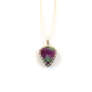 Peut inclure: Un collier avec un pendentif en pierre précieuse verte et rose sur un cordon blanc. La pierre précieuse est sertie dans une cage de fil.