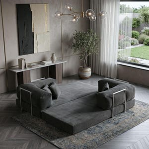 Puede incluir: Un sal&oacute;n moderno con un sof&aacute; modular gris con detalles met&aacute;licos plateados, colocado sobre una alfombra estampada. La habitaci&oacute;n incluye una ventana grande, una pintura decorativa y una l&aacute;mpara de ara&ntilde;a.