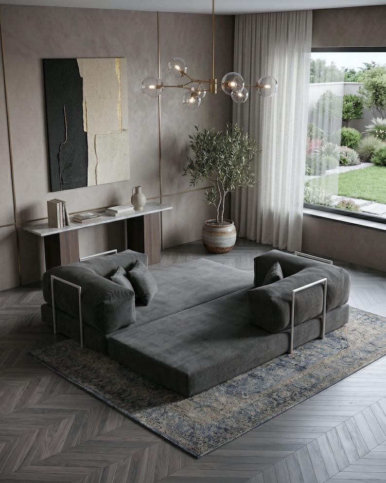 Puede incluir: Un sal&oacute;n moderno con un sof&aacute; modular gris con detalles met&aacute;licos plateados, colocado sobre una alfombra estampada. La habitaci&oacute;n incluye una ventana grande, una pintura decorativa y una l&aacute;mpara de ara&ntilde;a.