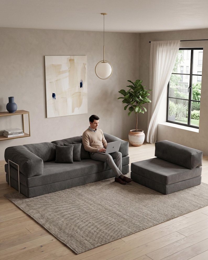 May include: A modern gray modular sofa and matching armchair set. The sofa has a low profile with square cushions and metal accents. The armchair is a single-seat version. The set is placed on a patterned rug in a neutral-toned living room.