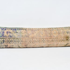 May include: A long, rectangular throw pillow with a colorful, vintage-style patterned fabric. The pillow is made of a soft, woven material and has a faded, distressed look.