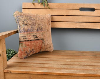 Könnte beinhalten: Eine Holzbank mit einem Kissen mit einem bunten, gemusterten Design. Das Kissen ist aus gewebtem Stoff mit verschiedenen Farben und Texturen.