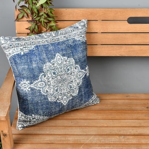 May include: A blue and white patterned throw pillow with a decorative design. The pillow is sitting on a wooden bench.