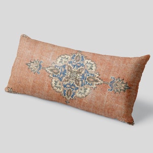 May include: A long, rectangular pillow with a peach-colored fabric featuring a blue and cream-colored geometric pattern.