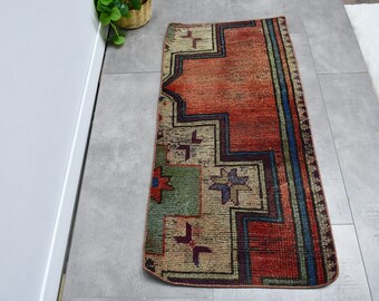 May include: A vintage runner rug with a geometric pattern in shades of red, blue, green, and beige. The rug has a distressed look and is perfect for adding a touch of bohemian style to your home.